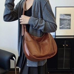 Brown leather crescent hobo bag with adjustable strap and front pocket detail