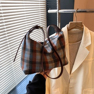 Sac fourre-tout à carreaux rétro avec bandoulière en cuir marron tenu à la main pour l'automne