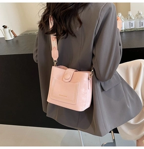 Pink bucket bag with embroidered wide strap shown on a grey blazer outfit for style