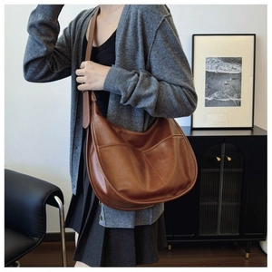 Detail of brown matte leather hobo bag featuring double front arc pockets and stitching