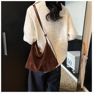 Sac bandoulière marron en daim mat de forme demi-lune porté par un mannequin