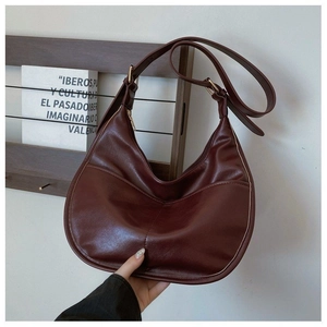 Detail of burgundy dumpling handbag featuring fine stitching and polished metal buckle