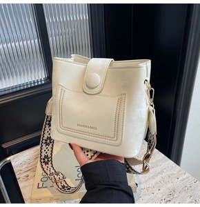 Detail of cream bucket bag with black and white retro woven wide shoulder strap