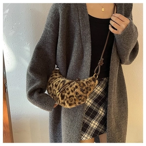Detail of leopard print crescent bag featuring soft faux fur and knotted leather strap
