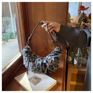Detail of leopard print plush crescent bag with brown knotted leather strap on a windowsill