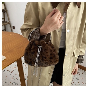 Detail of faux fur bucket bag featuring silver ring handle and chain tassel decoration