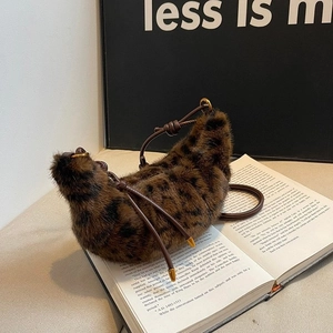 Winter faux fur leopard print crescent bag with brown leather strap on books