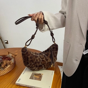 Detail of leopard print faux fur crescent bag with knotted strap on fashion magazine