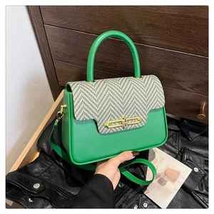 Detail of green leather handbag featuring herringbone fabric flap and gold metal ring clasp