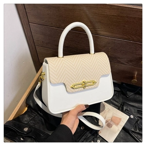 Detail of color-block PU leather handbag with gold metal clasp and woven fabric texture