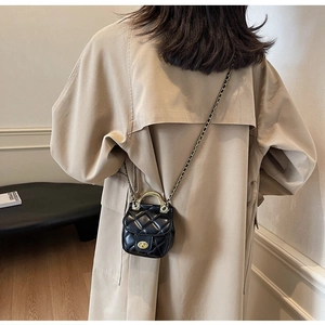 Détail d'un mini sac matelassé noir avec poignée en métal doré et bandoulière chaîne