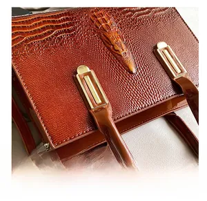 Details einer braunen Krokodilmuster-Handtasche mit goldener Hardware und Nähten