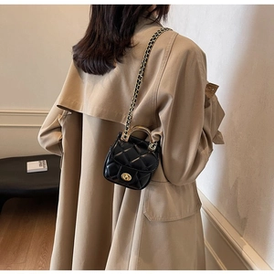 Détail d'un mini sac matelassé noir avec poignée en anneau doré et fermoir rotatif