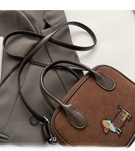 Détail de la broderie teckel sur sac bandoulière en daim marron avec anses en cuir