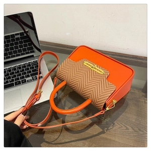 Detail of orange leather Kelly bag featuring brown herringbone woven flap and gold metal clasp