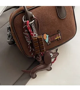 Détail de sac à main marron en daim avec broderie et breloques de chien en cuir