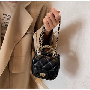 Détail d'un mini sac matelassé avec poignée en métal doré et bandoulière en chaîne