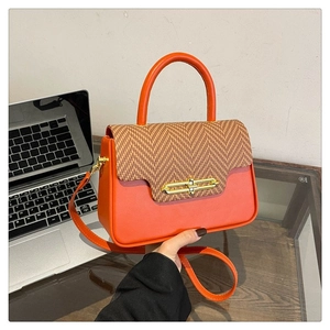 Detail of orange PU leather Kelly bag with golden lock and herringbone texture flap