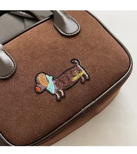 Détail du sac à main en daim marron foncé avec broderie cartoon de chien teckel
