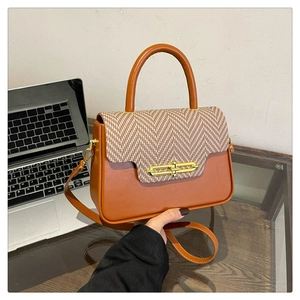 Detail of a brown leather and herringbone fabric handbag with a golden clasp