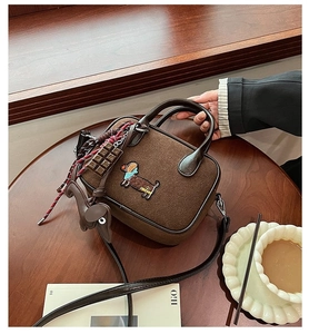 Détail du sac à main marron rétro avec broderie de teckel posé sur une table en bois