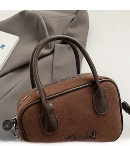 Vue détaillée des poignées en cuir et de la broderie fine sur le sac en daim marron foncé