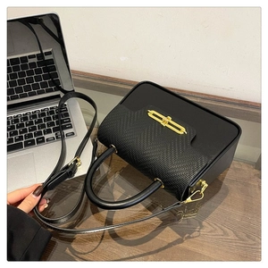 Close-up of black PU leather Kelly bag featuring a woven flap and gold metal hardware lock