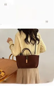 Detailed view of deep brown matte suede handbag with gold buckle on casual outfit