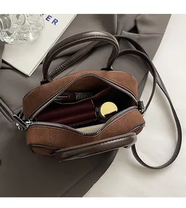 Détail du mini sac bandoulière en daim marron montrant l'espace intérieur et le zip