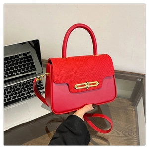 Close-up of bright red Kelly bag featuring woven texture and gold metal buckle closure