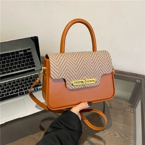 Detail view of brown PU leather handbag with herringbone pattern flap and gold lock