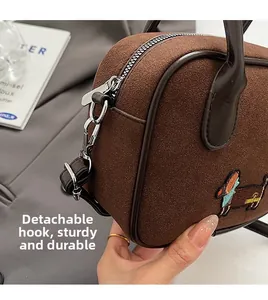 Détail du sac en daim marron foncé avec broderie teckel et fermoirs argentés