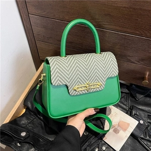 Detail of green PU leather Kelly bag with black and white tweed flap and gold twist lock