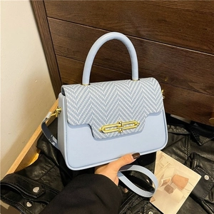 Detail of light blue PU handbag with golden chain lock and textured woven flap cover