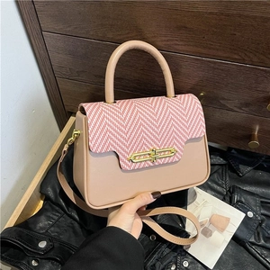 Detail of crossbody bag featuring pink leather, herringbone weave flap and gold lock