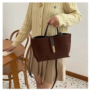 Detail of dark brown frosted suede handbag with golden metal buckle and top handle