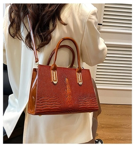 Detailaufnahme der weinroten Crossbody-Tasche mit Krokoprägung und Goldbeschlägen