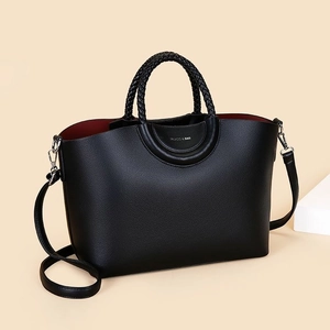 Black PU leather crossbody bag with woven handles and red lining in a 45-degree view