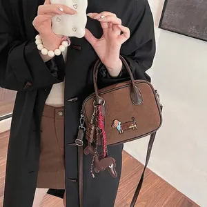 Sac bandoulière en daim marron avec broderie teckel et breloques mignonnes sur fond neutre