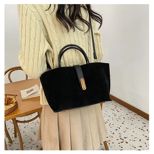 Detail of black suede shoulder bag with elegant gold metal buckle closure for women