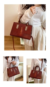 Details der dunkelroten Handtasche mit Krokodilmuster, Goldbeschlägen und Schultergurt