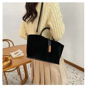 Detail view of the black matte leather handbag featuring a golden long buckle and strap