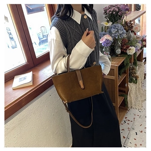 Close-up of brown matte suede tote bag featuring leather straps and gold metal buckle