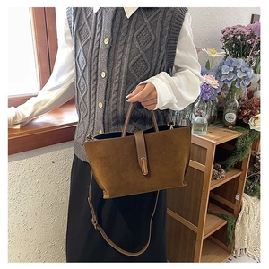 Detail of the dark brown suede handbag with a minimalist golden oval buckle and slim strap