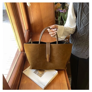 Close-up of brown matte leather handbag with vintage gold buckle on a wooden window sill