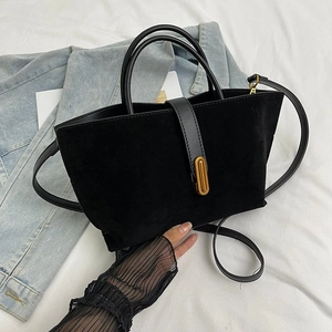 Detail of black matte suede handbag with smooth leather straps and gold metal buckle