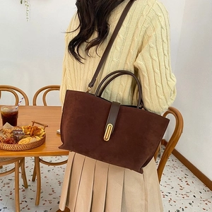 Detail of a dark brown frosted tote bag showing the texture and metal buckle on a woman