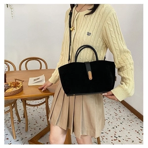 Matte black crossbody bag with gold lock buckle and dual handles in daily setting