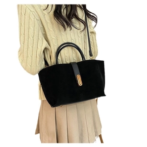 Matte black tote bag with gold buckle and adjustable strap shown on model in studio view
