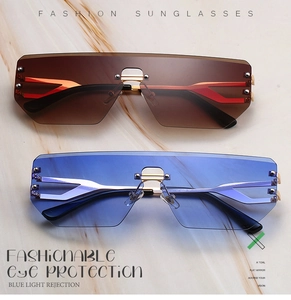 Detail view of rimless shield sunglasses with metal rivets and colored marble background